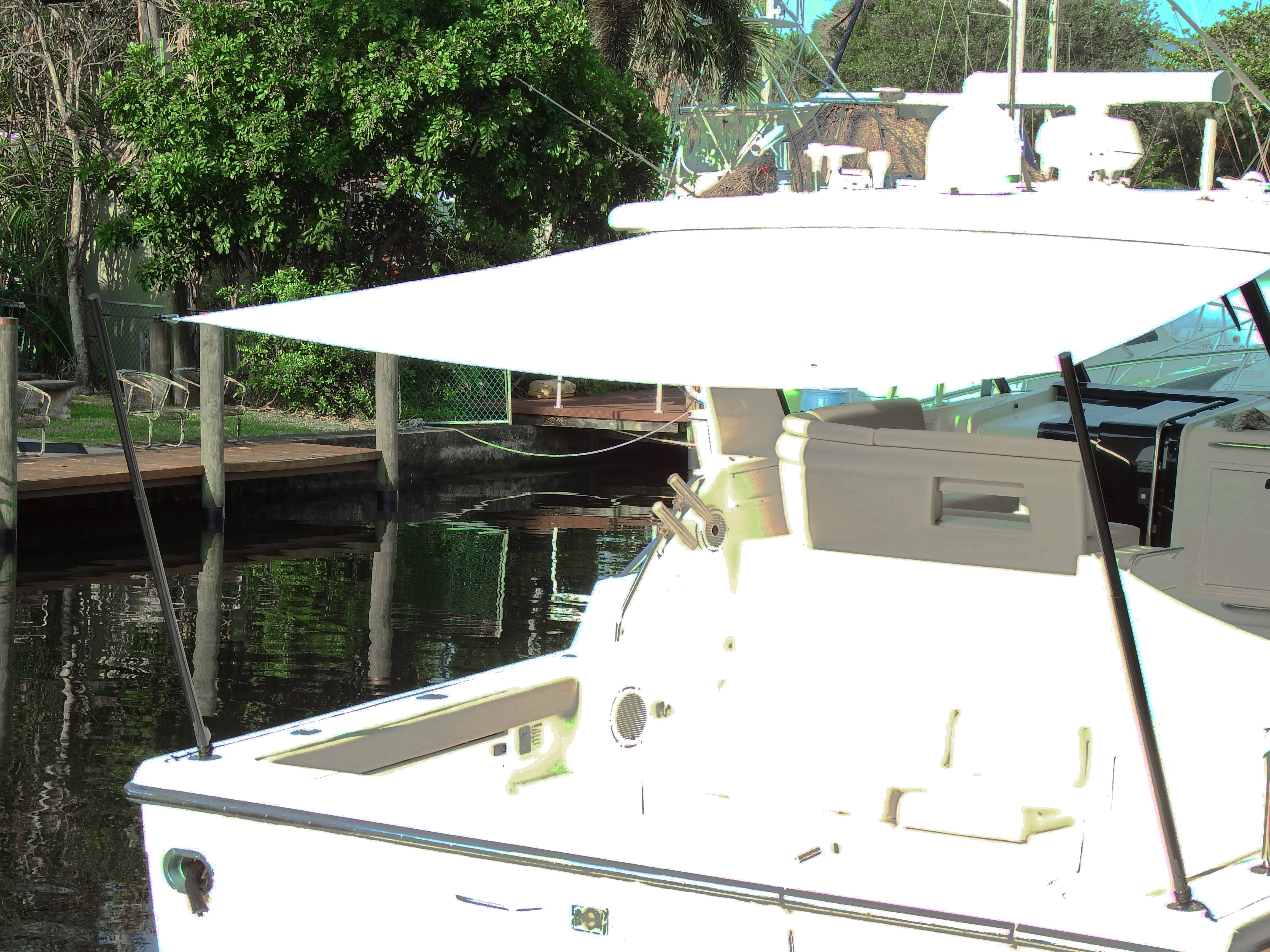 A white boat with a white shade held up with black carbon fiber Carbiepoles.